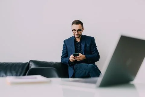 Handsome freelancer working remotely from home. He is using phone. Stock Photos