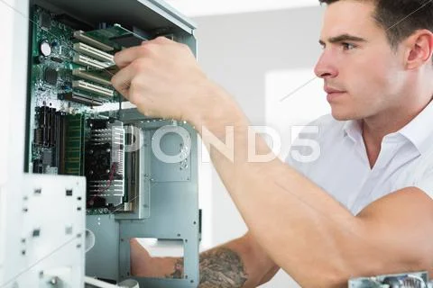 Handsome frowning computer engineer working at open computer Stock Photos
