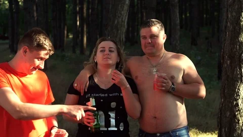 Handsome, funny mimicry guy in a red T-shirt, with a beer and a clock for fun Video stock 107724316