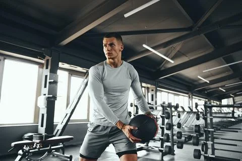 Handsome good looking guy doing workout using fitness medicine ball at modern Stock Photos