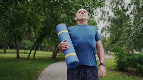Handsome Gray-Haired Old Man Standing in Park with Sport Mat and Looking in Stock Footage 148464483