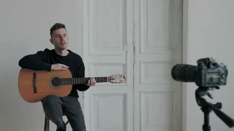 Handsome guitar player is recording tutorial about music skills for internet Stock Footage 107812266