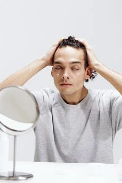 Handsome guy applying cream on the face and looking in the mirror cosmetology Stock Photos