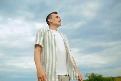 Handsome guy on the background of the sky and the field. Men's fashion, unity Stock Photos