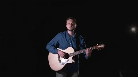 Handsome guy with beard playing acoustic guitar. Black background. Isolated Stock Footage 135234394