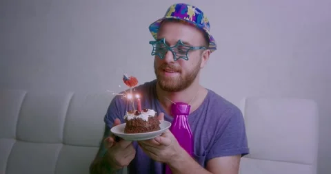 Handsome guy blowing out the candles on a delicious birthday cake Stock Footage 144003750
