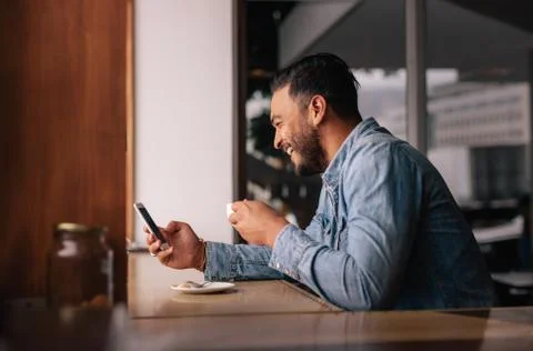 Handsome guy at cafe using smart phone and having coffee Stock Photos