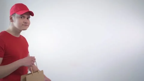 A handsome guy from the delivery service hands the parcel in an eco package. Stock Footage 132463958