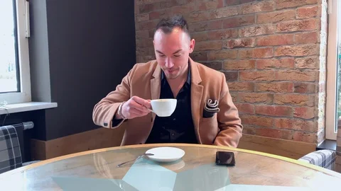Handsome guy drinks big coffee alone in a cafe Stock Footage 128285800