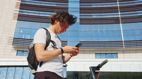 Handsome guy with e-scooter stands near building Stock Footage 186516279