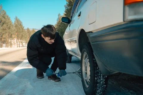 Handsome guy fixing a car by changing a wheel Stock Photos