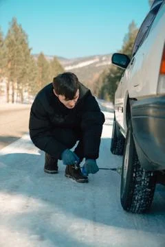 Handsome guy fixing a car by changing a wheel Stock Photos