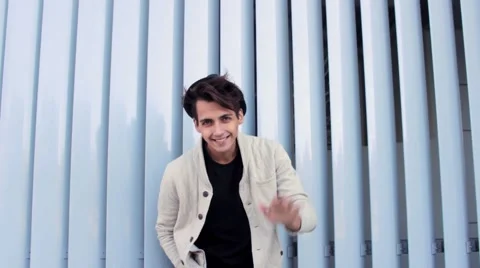 Handsome guy in a hat smiling and waving at the camera. Man model looks very 스톡 동영상 54684244