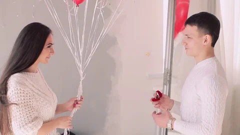 Handsome guy on his knees proposing girl to marry him holding hands of his 스톡 동영상 74025836