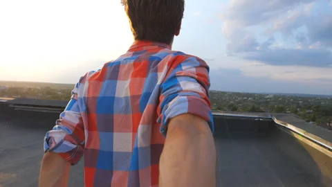 Handsome guy holds hand of his boyfriend and runs to edge of roof to admire view Stock Footage 125449745