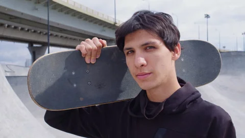 Handsome guy keep skateboard on shoulder at street Video stock 255804363