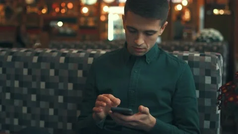 Handsome guy, looking around and using his smartphone, sitting in a cafe Video stock 107607186