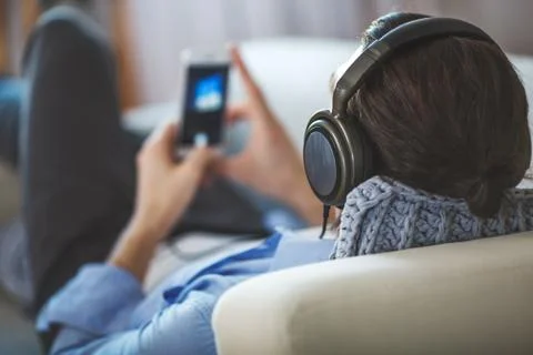 Handsome guy lying on sofa with tablet and headphones Stock Photos