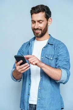 Handsome guy perfect appearance browsing telephone against blue copy space Stock Photos