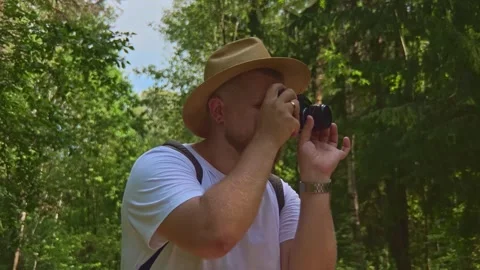 Handsome guy photographing green trees around. Adventure, hiking concept Stock Footage 252600731
