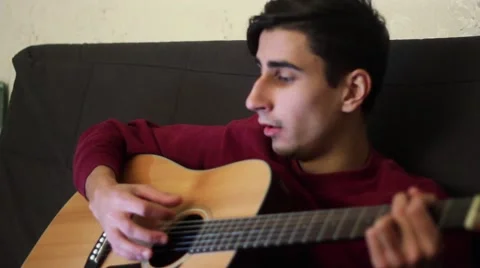 Handsome guy plays guitar and sings a song. Stock-Footage 59728663
