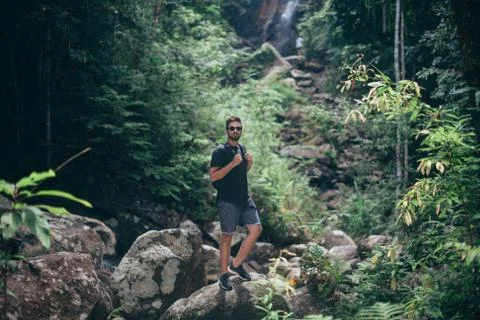 Handsome guy on the rocks at a tropical waterfall. Foto stock