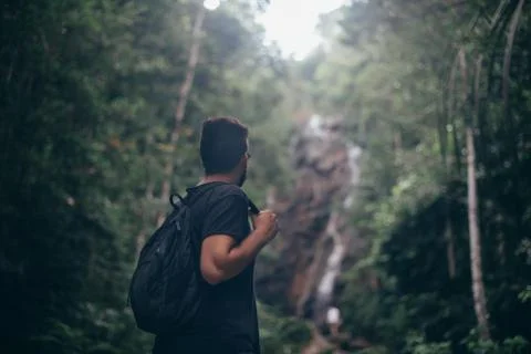 Handsome guy on the rocks at a tropical waterfall. Stock Photos
