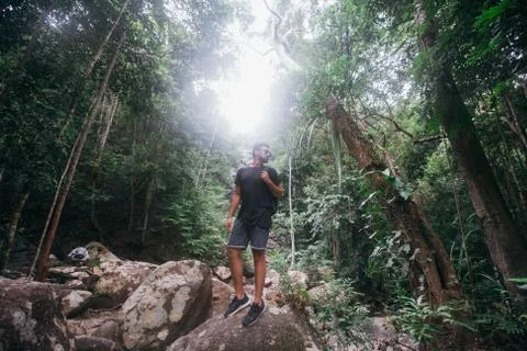 Handsome guy on the rocks at a tropical waterfall. Stock Photos