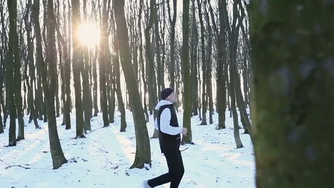 Handsome guy running in the forest in winter time. Fatigue after jogging 動画素材 76193827