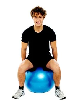Handsome guy seated on exercise ball Stock Photos
