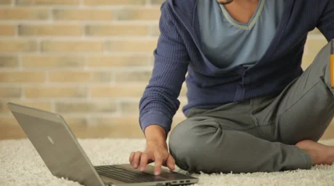 Handsome guy sitting on floor using laptop and drinking juice Stock Footage 28791820