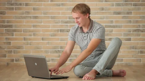 Handsome guy sitting on floor using laptop closing it and smiling at camera Video stock 34278252