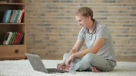 Handsome guy sitting on floor using laptop holding credit card and smiling  動画素材 34278287