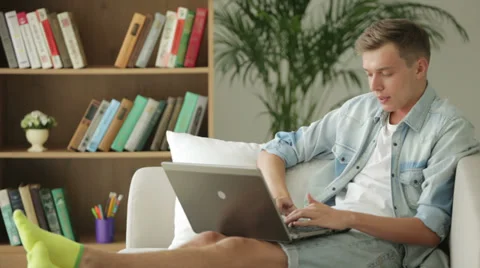 Handsome guy sitting on sofa and using laptop Stock Footage 27691975