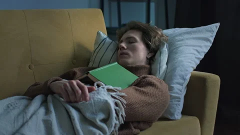 Handsome guy is sleeping after reading the book lying at the sofa Stock Footage 146310011