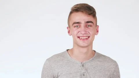 Handsome guy smiling looking at the camera. A guy standing on a white 스톡 동영상 58628414