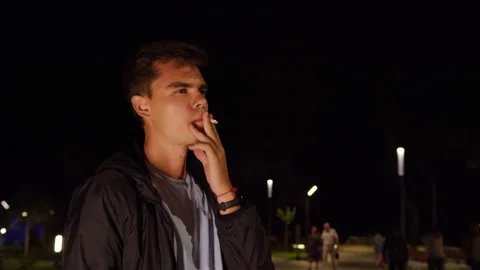Handsome guy smokes cigarette standing on street Video stock 165504202