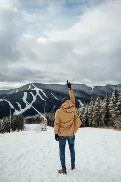A handsome guy stands with his back and enjoys the view of the winter mountains Stock Photos