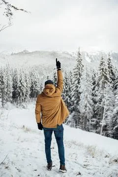 A handsome guy stands with his back and enjoys the view of the winter mountains 스톡 사진