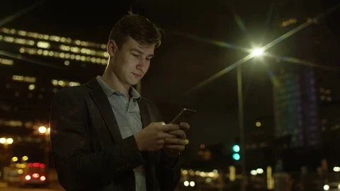 Handsome guy is texting while standing on a street Stock Footage