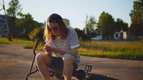 Handsome Guy Type a Message Standing Near a Bicycle at Sunset. Stock Footage 80008104