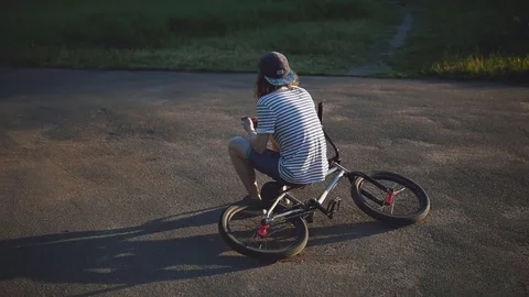 Handsome Guy Type a Message Standing Near a Bicycle at Sunset. Stock Footage 80008466