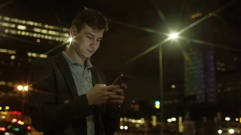 Handsome guy is typing a text message while standing on a street Stock Footage 77578023