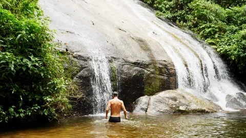 Handsome guy under waterfall Stock Footage 94106750