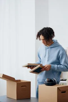 Handsome guy unpacking things from boxes in the room sorting things out Stock Photos