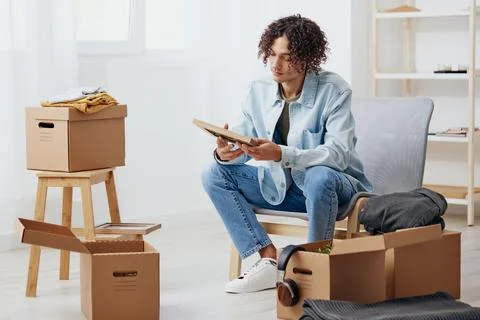 Handsome guy unpacking things from boxes in the room sorting things out Stock Photos
