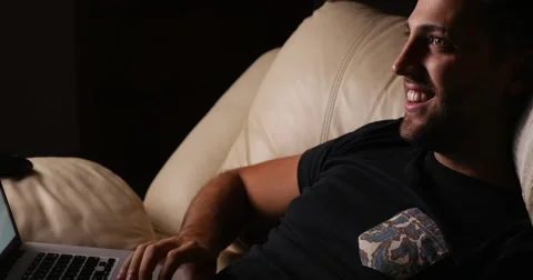 Handsome guy using his laptop on the sofa Video stock 62358685