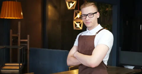 Handsome guy waiter prepares empty hall of restaurant, cafe before opening. Video stock 136074750