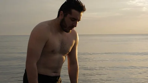 Handsome guy washes face with ocean water at sunrise Stock Footage 124024714