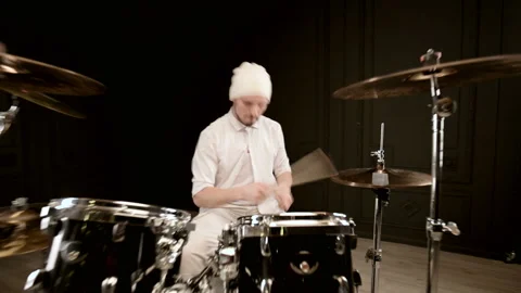 Handsome guy in white actively plays on drum kit in on black background. Closeup Stock Footage 121741084